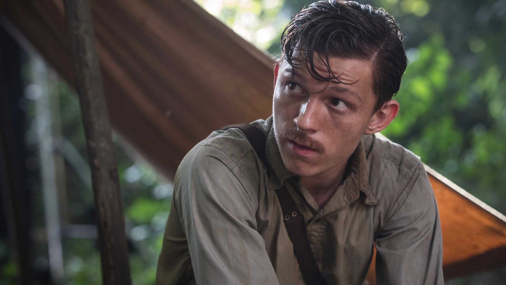 تام هالند در فیلم The Lost City of Z در جنگل نشسته است
